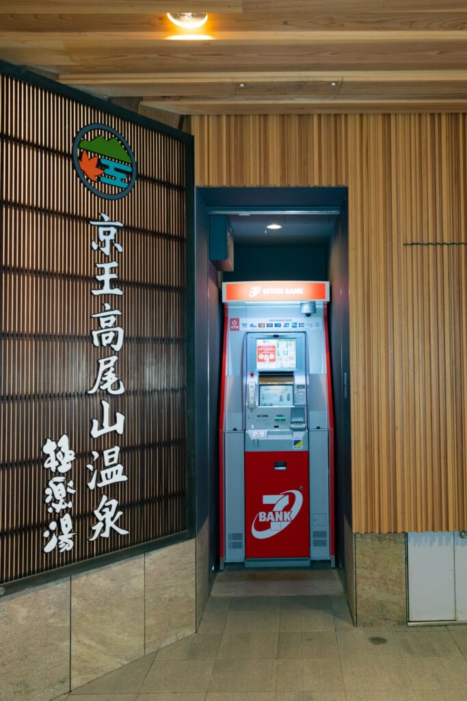 高尾山口駅の改札外、京王高尾山温泉 極楽湯の看板の右側にあるセブン銀行のATM