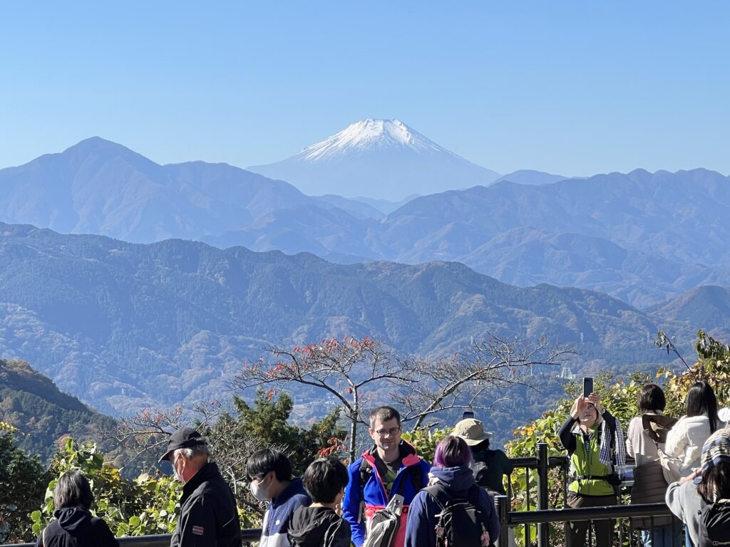 高尾山頂から見た富士山と丹沢の山並み。展望台に人が集まる