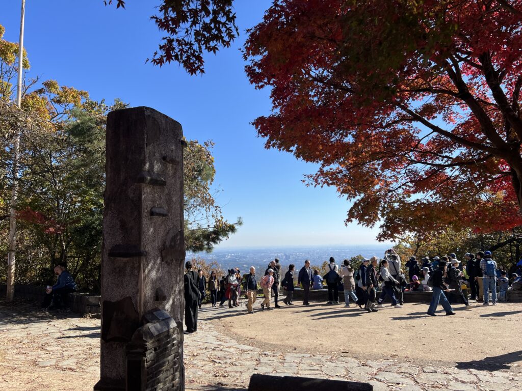 紅葉の季節の昼前、高尾山頂の広場に集まる人たち