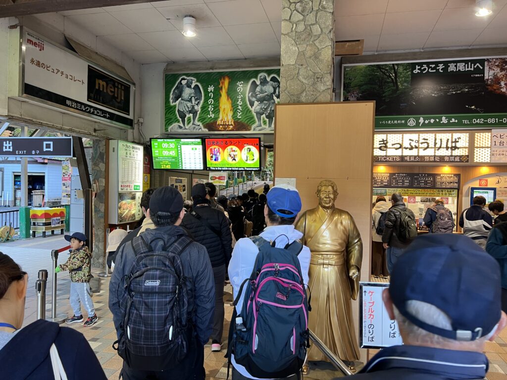 紅葉の季節の朝、ケーブルカー清滝駅のきっぷ売り場に並ぶ人たち